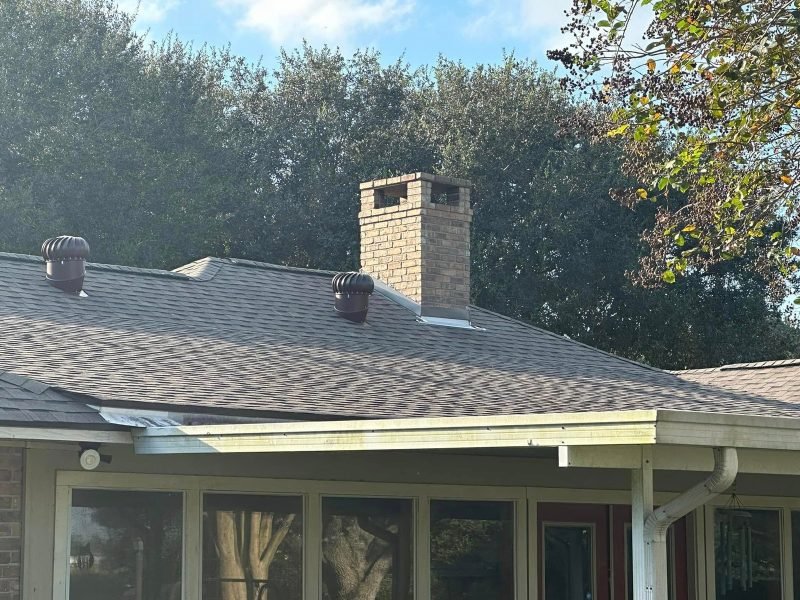 New shingles around a brick chimney and two turbine vents above a screened porch