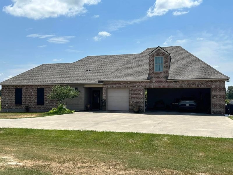 Brick home with a new dark roof, a front gable and double garage on a wide drive