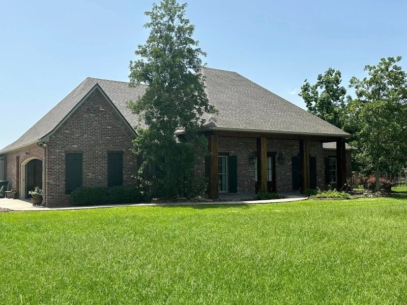 Brick home with a new gray shingle roof and a porch on wood posts