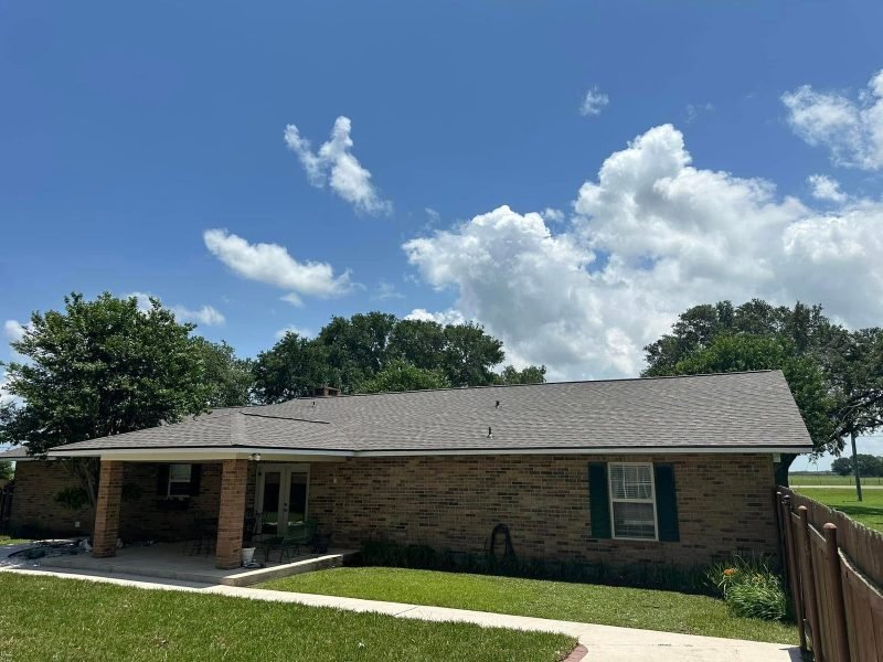 Brick ranch home with a new gray roof extending over a side porch