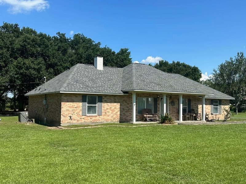 Brick ranch home with a new gray hip roof, chimney and a white-columned front porch