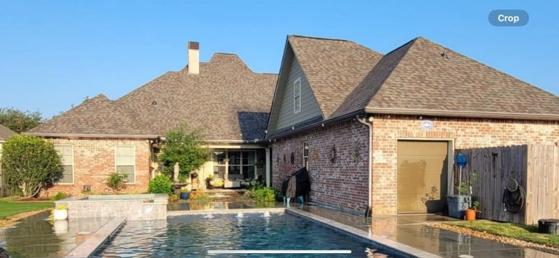 Brick home with steep new brown shingle roofs around a courtyard pool