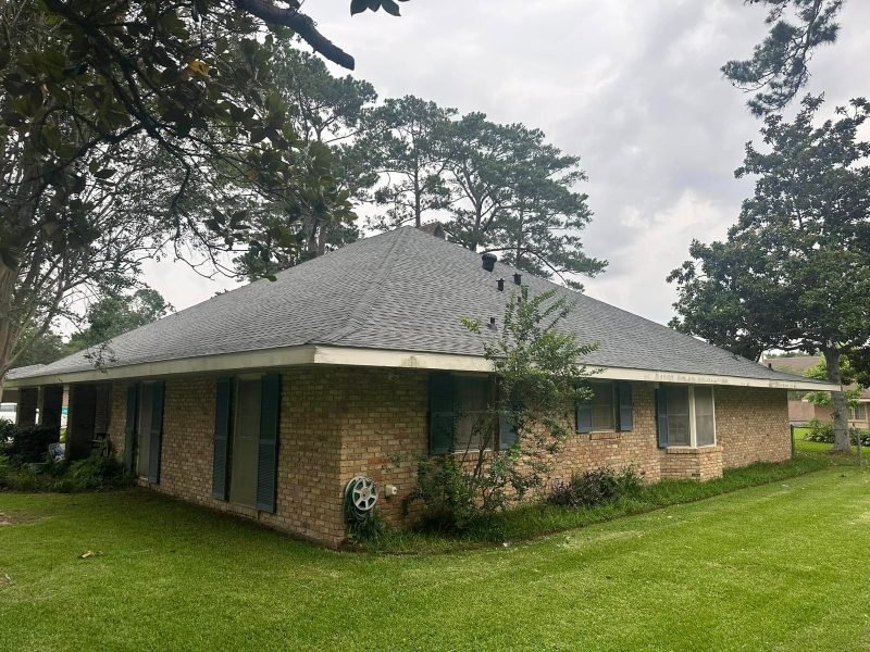 Long, low brick ranch home with a new gray shingle hip roof and dark shutters