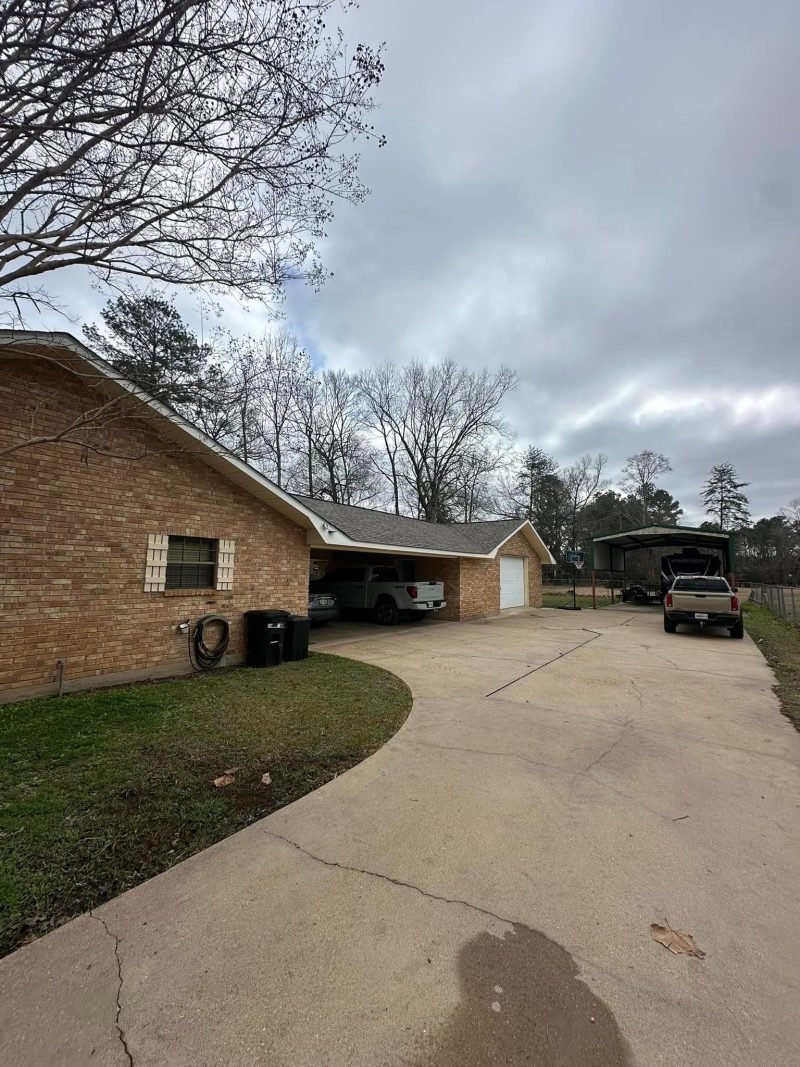Brick ranch home with a new roof and attached carport beside a long concrete driveway