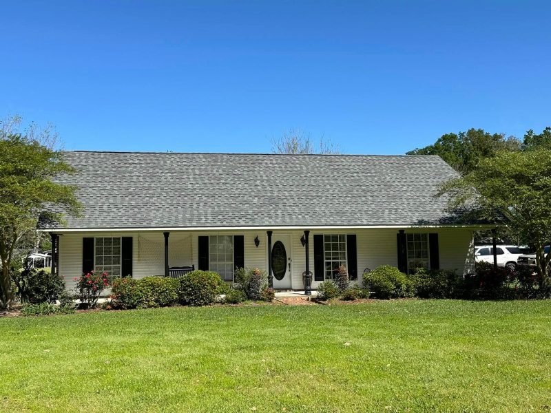 White ranch home with a long front porch and a new gray shingle roof