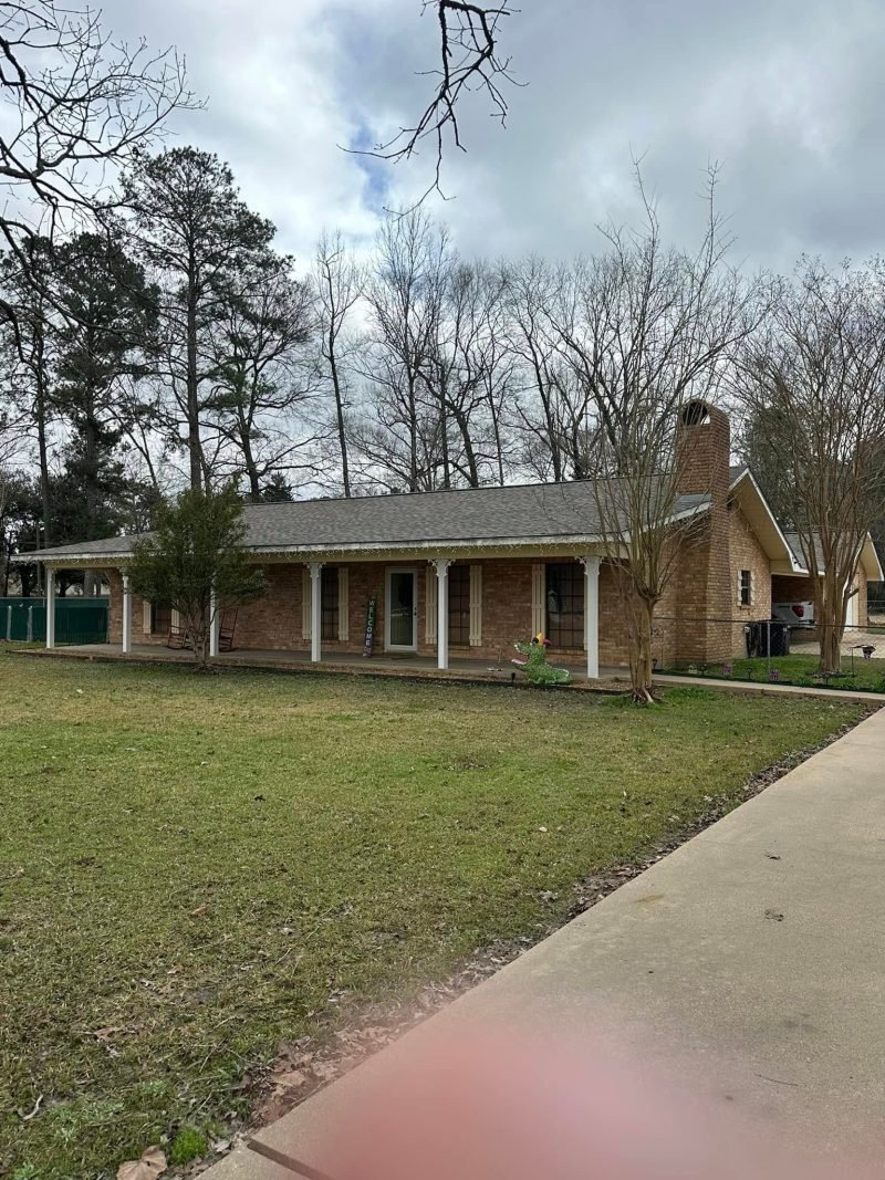 Brick ranch home with a long front porch and a new roof seen from the sidewalk