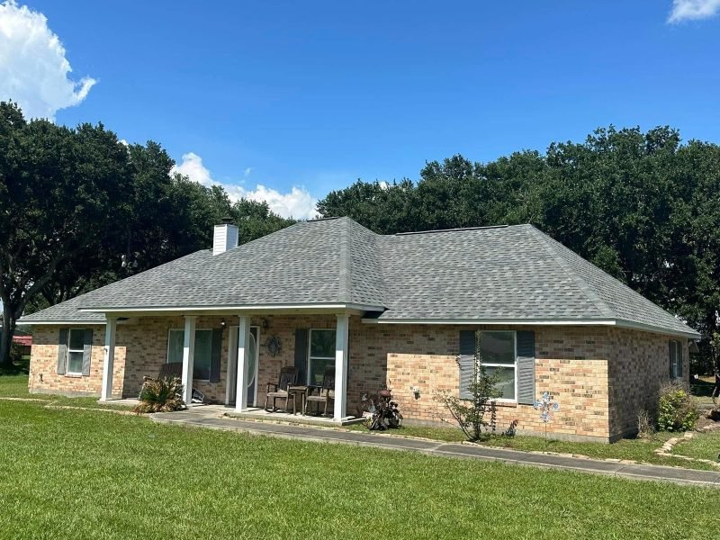 Tan brick ranch home with a new gray hip roof and a covered front porch