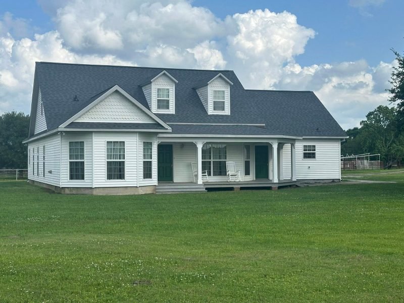 White-sided home with two dormers, a front porch and a new dark gray roof