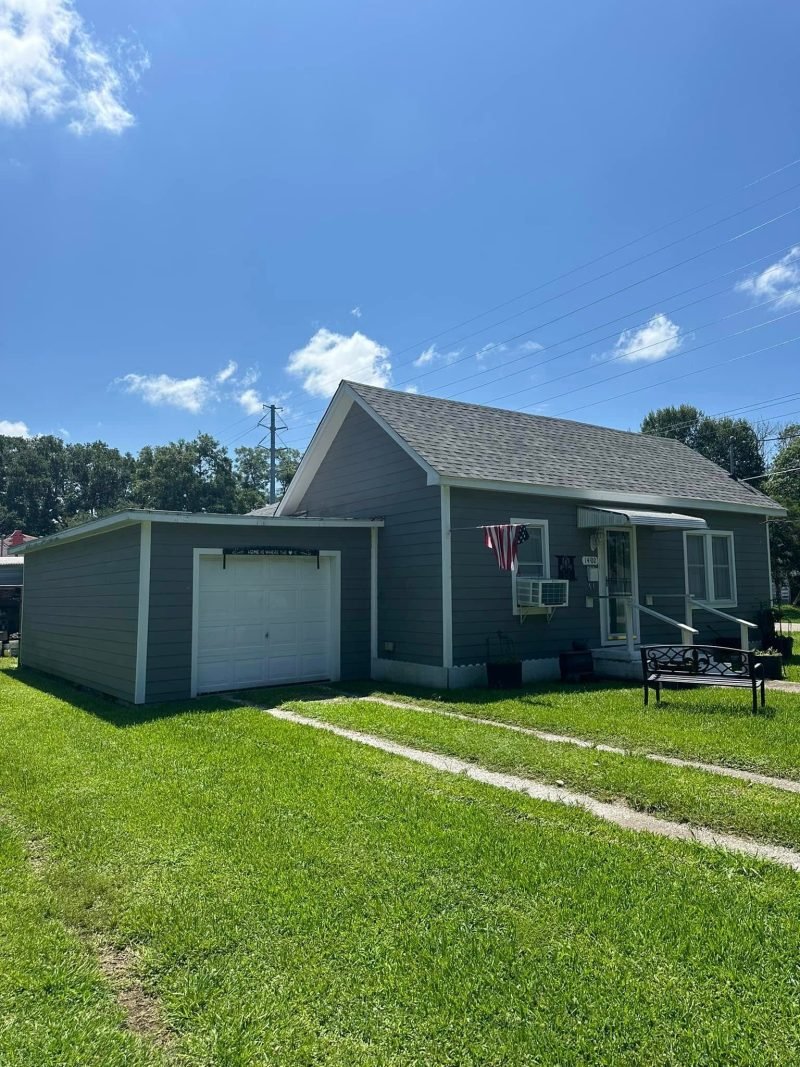 Home with gray siding, a detached garage and new gray roofs