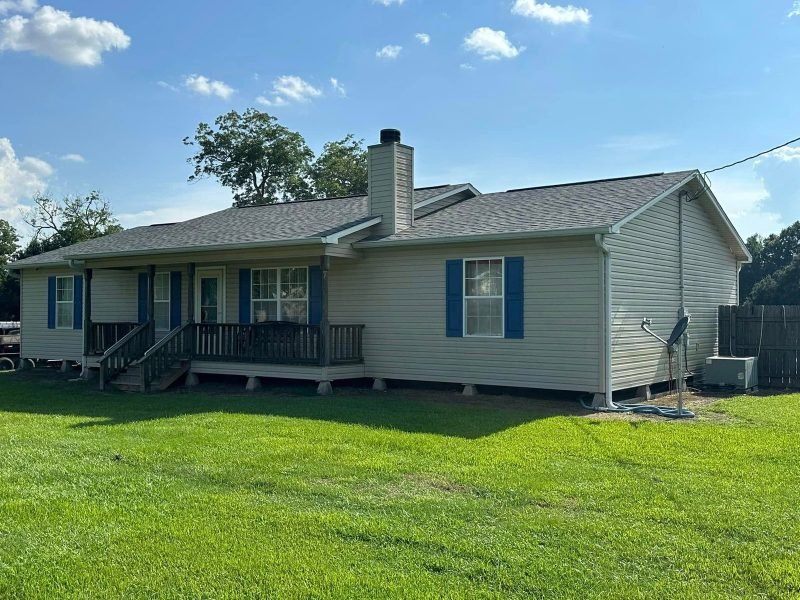 Raised home with light siding, blue shutters, a front porch and a new gray roof
